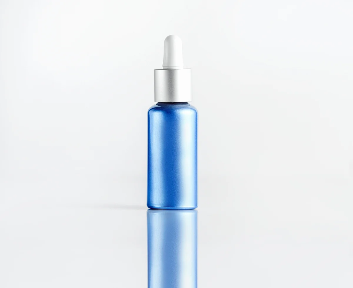 Source photograph of an unbranded blue dropper bottle with a silver collar and white pipette cap