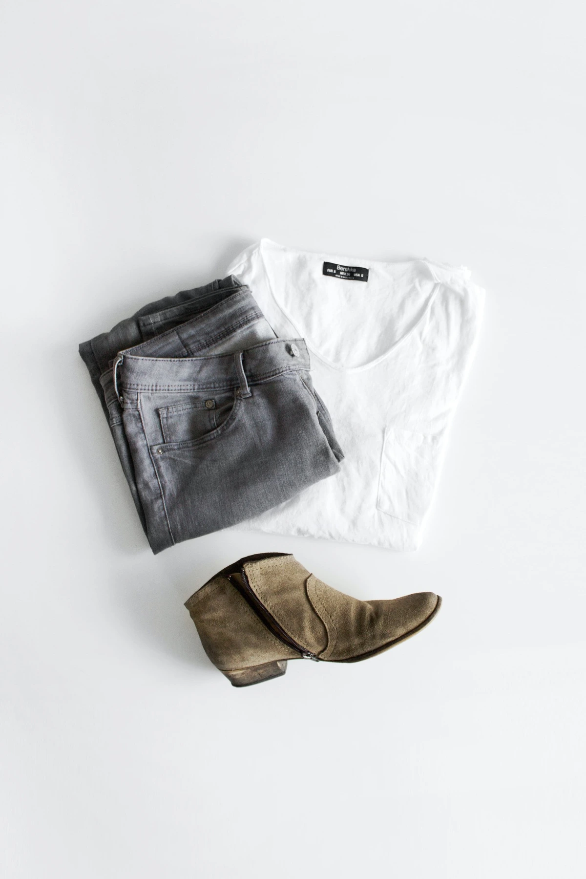 Original flatlay photo of a white T-shirt, folded grey jeans and a brown ankle boot