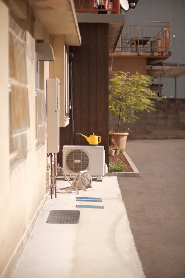 Original stock photo of an outdoor air-conditioning unit beside a residential building