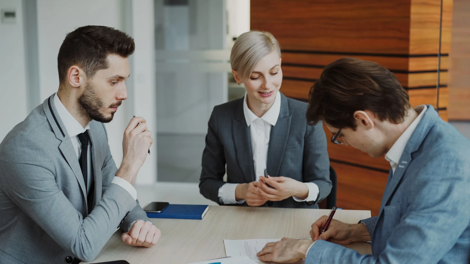 Supplied photograph of three adults discussing documents around a consultation table