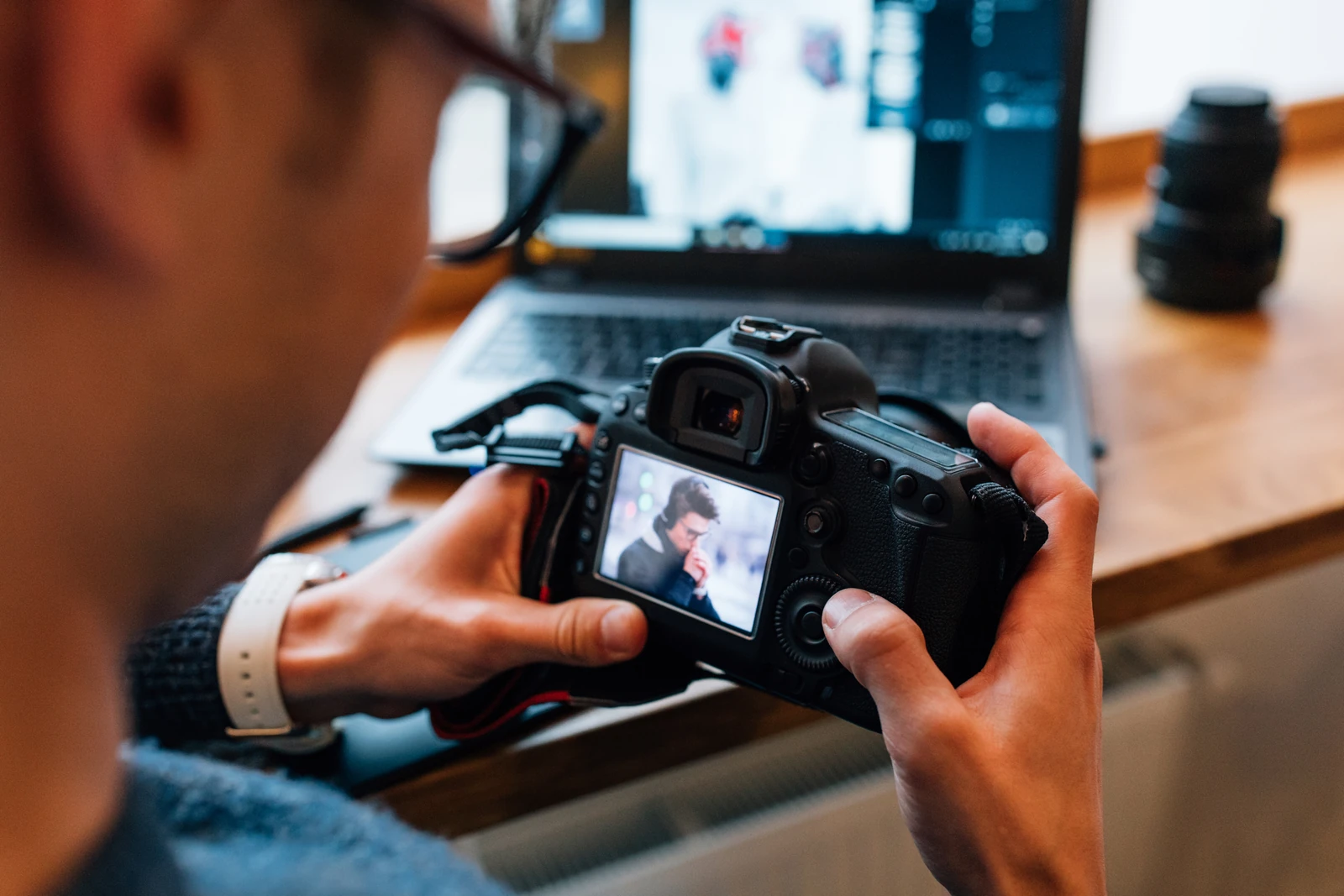 Source photograph of a person reviewing a portrait on a camera screen beside a laptop