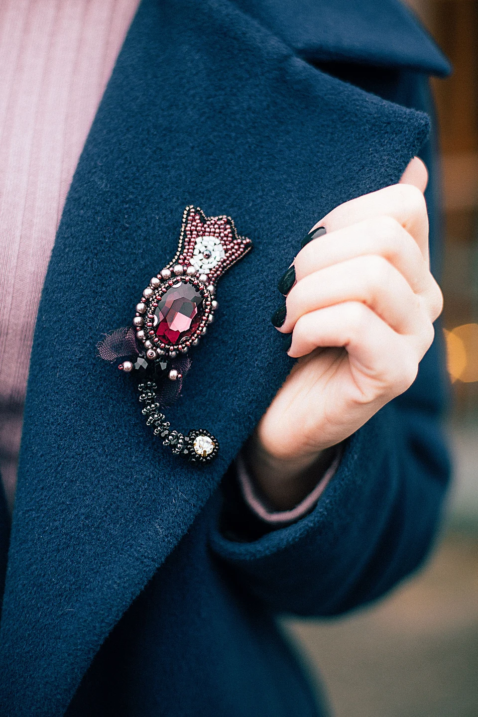 Close-up of a burgundy beaded brooch pinned to a blue coat