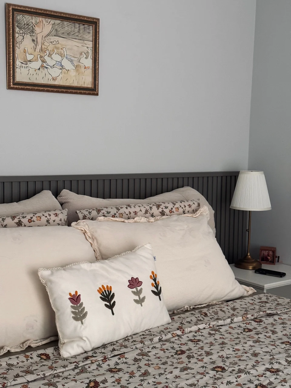 Bedroom interior with patterned bedding, embroidered cushions and a bedside lamp