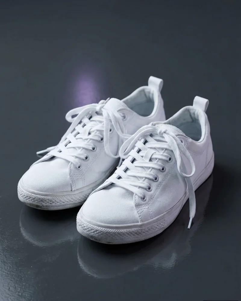 White trainers photographed on a dark studio surface, an illustrative product-photography service example